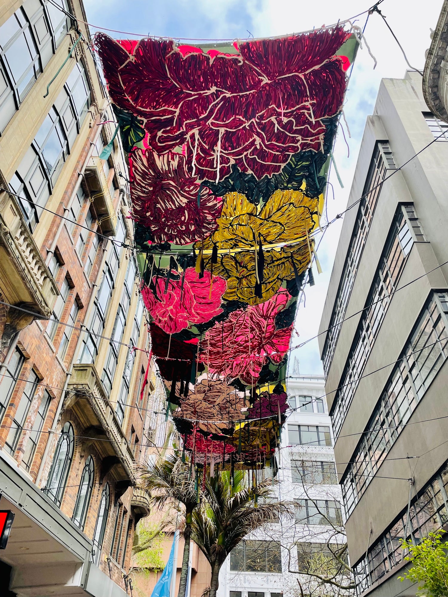 9 meter embroidered canopy suspended above Auckland city street, made from recycled materials, vibrant floral colours